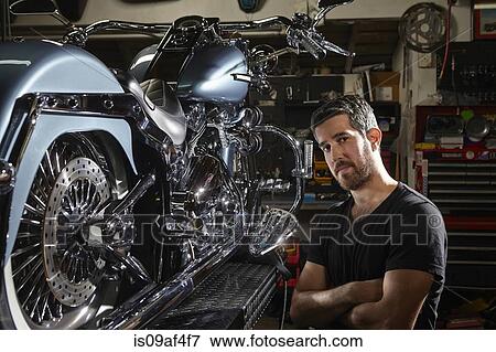 Stock Photo - Portrait of mid adult man in motorcycle repair workshop. Fotosearch