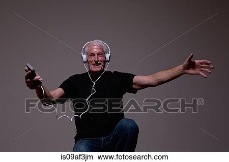 Picture - Portrait of senior man dancing to MP3 player on headphones. Fotosearch