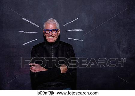 Stock Image - Portrait of senior man in front of chalked lines on blackboard. Fotosearch