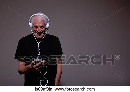 Portrait of senior man wearing headphones and using MP3 player View Large Photo Image Picture - Portrait of senior man wearing headphones and using MP3 player. Fotosearch
