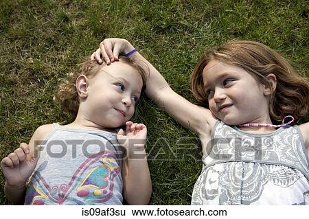Portrait of two young sisters lying on grass View Large Photo Image Stock Photograph - Portrait of two young sisters lying on grass. Fotosearch