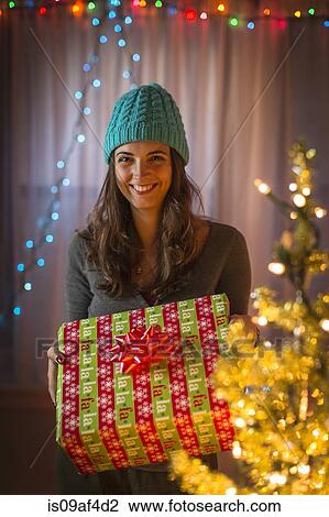 Portrait of young woman holding christmas gift View Large Photo Image Stock Image - Portrait of young woman holding christmas gift. Fotosearch