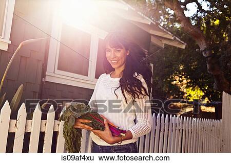 Portrait of young woman holding homegrown vegetables View Large Photo Image Stock Photograph - Portrait of young woman holding homegrown vegetables. Fotosearch