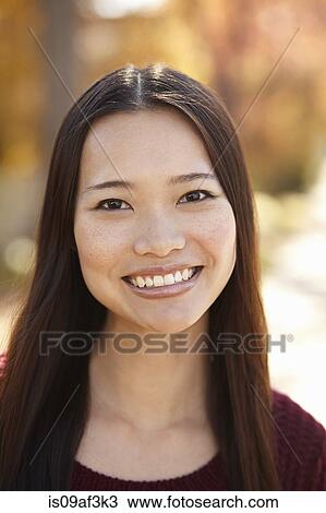Stock Image - Portrait of young woman in park. Fotosearch