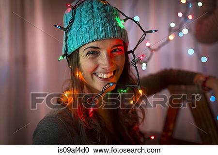 Stock Image - Portrait of young woman wrapped in christmas lights. Fotosearch