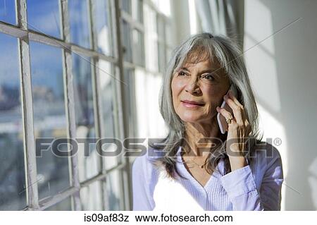 Senior woman looking out of window whilst using smartphone View Large Photo Image Stock Photo - Senior woman looking out of window whilst using smartphone. Fotosearch