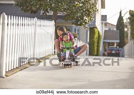 Siblings cycling on driveway View Large Photo Image Stock Image - Siblings cycling on driveway. Fotosearch