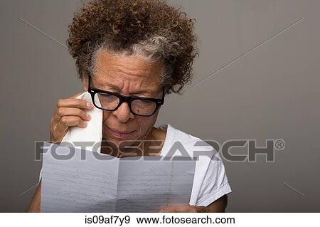 Stock Photo - Studio portrait of sad senior woman reading a letter. Fotosearch