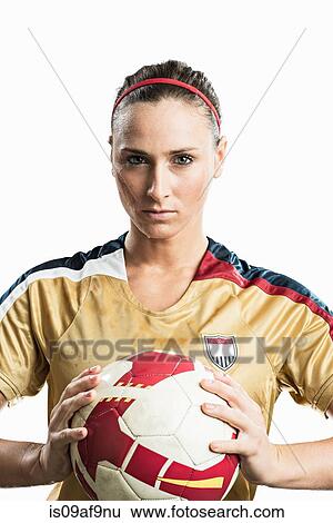 Stock Photograph - Studio portrait of young female soccer player holding ball. Fotosearch