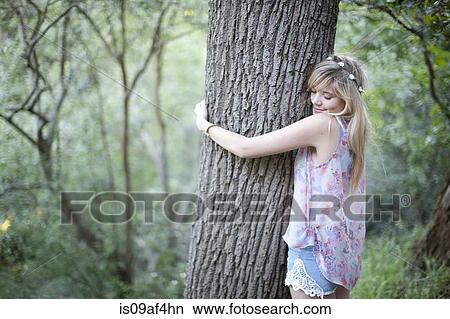 Picture - Teenage girl hugging tree in woodland. Fotosearch