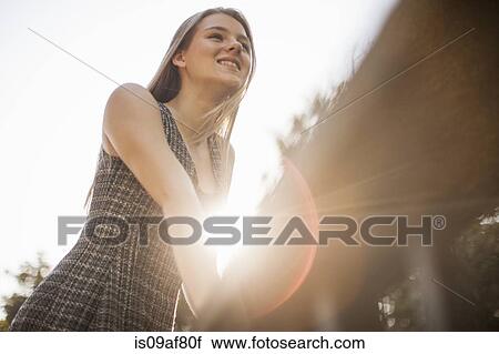 Stock Image - Teenage girl leaning on railings in park. Fotosearch
