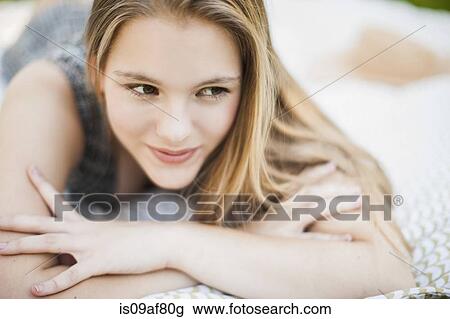 Stock Image - Teenage girl lying on picnic blanket. Fotosearch