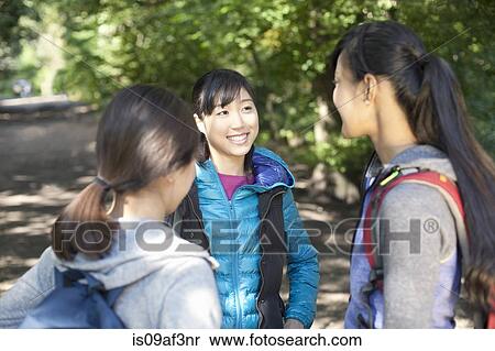 Stock Photography - Three young female hikers chatting on country road. Fotosearch