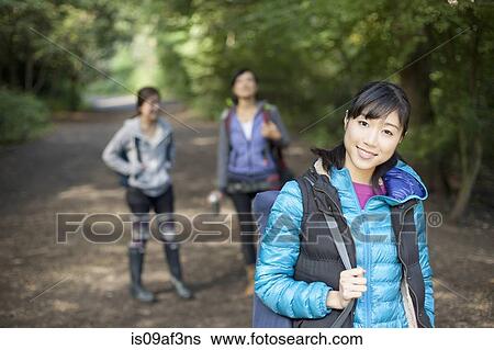 Stock Photograph - Three young female hikers on country road. Fotosearch