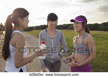 Stock Image - Three young female runners chatting after run. Fotosearch