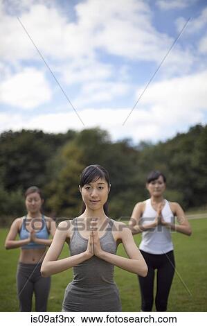 Stock Photo - Three young women in park practicing yoga. Fotosearch