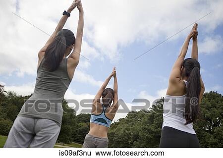Stock Photograph - Three young women practicing yoga in park. Fotosearch