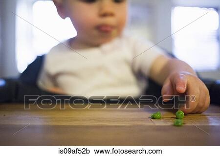 Stock Image - Toddler girl pointing at peas. Fotosearch