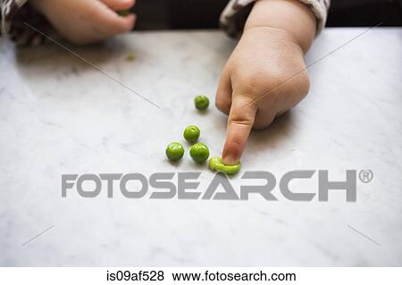Stock Photo - Toddler girl squashing pea. Fotosearch