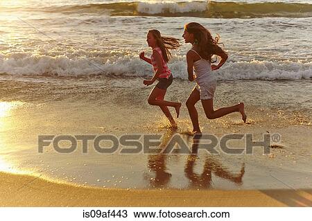Two girls running along beach at sunset View Large Photo Image Stock Image - Two girls running along beach at sunset. Fotosearch