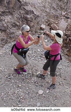 Stock Image - Two senior female hikers photographing each other. Fotosearch