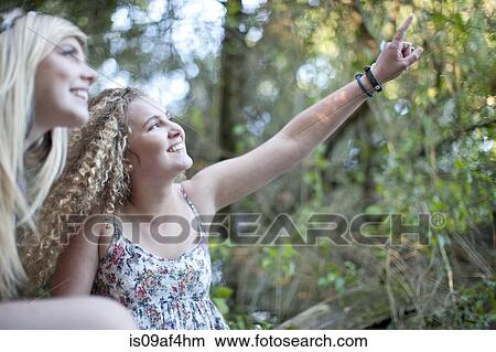Picture - Two teenage girls exploring in woodland. Fotosearch