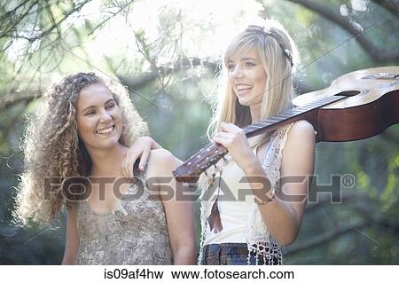 Stock Photo - Two teenage girls with acoustic guitar in woodland. Fotosearch