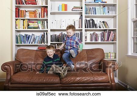 Stock Image - Two young brothers jumping on sofa. Fotosearch