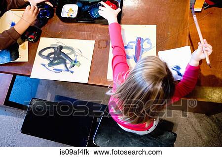 Stock Image - Two young siblings painting pictures at table. Fotosearch