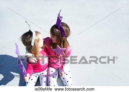 Stock Image - Two young sisters dressed up as fairies holding wands. Fotosearch