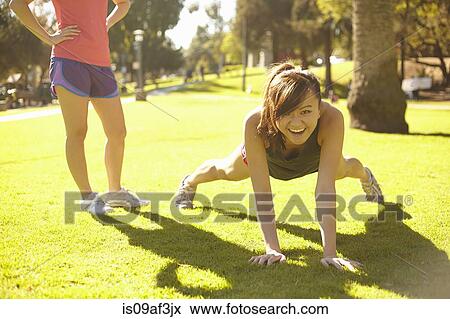 Two young women doing exercises in park View Large Photo Image Stock Photo - Two young women doing exercises in park. Fotosearch