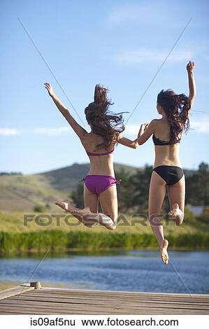 Stock Photograph - Two young women jumping from river pier. Fotosearch