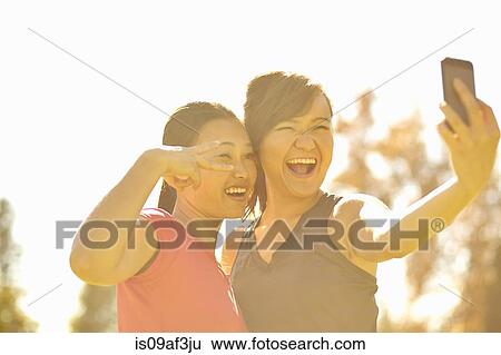 Two young women making self portrait in park View Large Photo Image Stock Photograph - Two young women making self portrait in park. Fotosearch