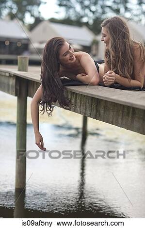 Two young women relaxing on river pier View Large Photo Image Stock Photo - Two young women relaxing on river pier. Fotosearch