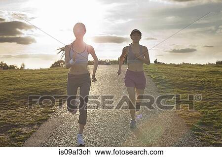Two young women running on dirt track View Large Photo Image Stock Image - Two young women running on dirt track. Fotosearch