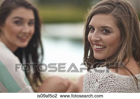Two young women sitting by riverside View Large Photo Image Stock Image - Two young women sitting by riverside. Fotosearch