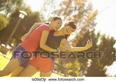 Stock Photography - Two young women taking self portrait in park. Fotosearch