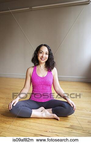 Picture - Woman sitting in lotus position on floor. Fotosearch