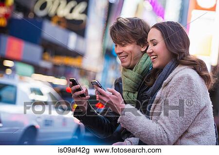 Young couple competing on cell phones, New York City, USA View Large Photo Image Stock Image - Young couple competing on cell phones, New York City, USA. Fotosearch