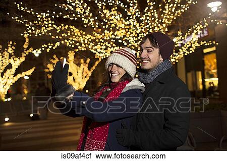Young couple enjoying christmas celebrations on street View Large Photo Image Stock Image - Young couple enjoying christmas celebrations on street. Fotosearch