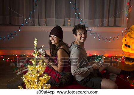 Young couple exchanging gifts in sitting room at christmas View Large Photo Image Stock Photography - Young couple exchanging gifts in sitting room at christmas. Fotosearch