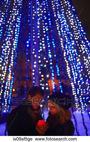 Stock Image - Young couple holding candle in front of city xmas lights. Fotosearch