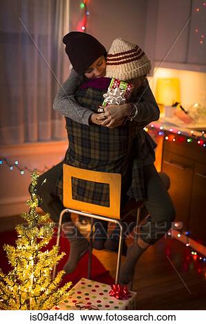 Stock Photo - Young couple hugging on chair at christmas. Fotosearch