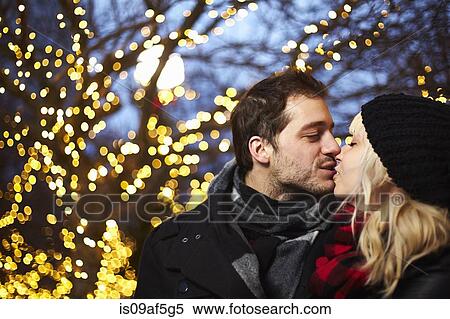 Young couple kissing in front of outdoor xmas lights View Large Photo Image Stock Photography - Young couple kissing in front of outdoor xmas lights. Fotosearch