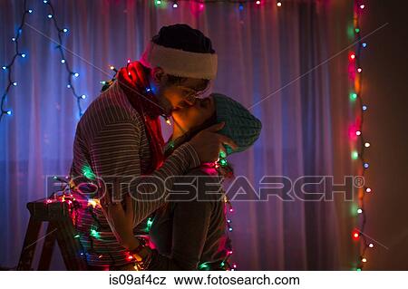 Young couple kissing whilst wrapped in fairy lights at christmas View Large Photo Image Stock Photo - Young couple kissing whilst wrapped in fairy lights at christmas. Fotosearch