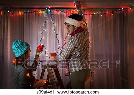 Young couple putting up fairy lights at christmas View Large Photo Image Stock Image - Young couple putting up fairy lights at christmas. Fotosearch