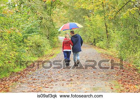 Young couple strolling along country lane with colorful umbrella View Large Photo Image Stock Image - Young couple strolling along country lane with colorful umbrella. Fotosearch
