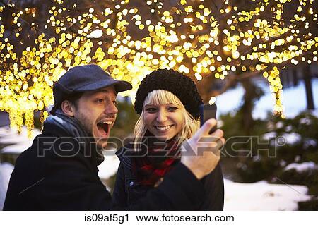 Young couple taking self portrait with outdoor xmas lights View Large Photo Image Stock Image - Young couple taking self portrait with outdoor xmas lights. Fotosearch