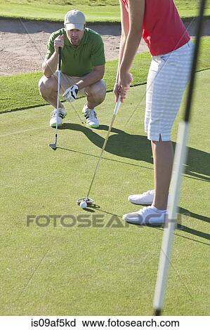 Young female lining up golf ball with trainer View Large Photo Image Stock Image - Young female lining up golf ball with trainer. Fotosearch