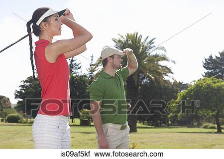 Stock Image - Young female practicing golf with trainer. Fotosearch